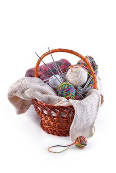 Balls of wool and knitting needles in basket isolated on a white background