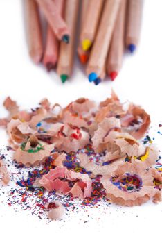 Multi-coloured pencil with crayon shavings, on white background