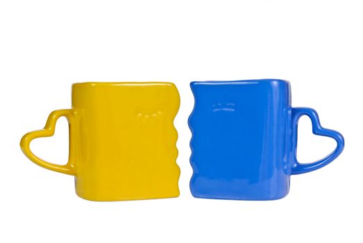 Yellow and blue mug with the handle in the form of heart, isolated on a white background