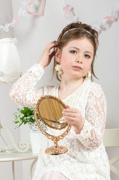 A beautiful little girl looking to small mirror