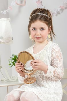 A beautiful little girl looking to small mirror