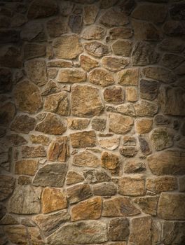 Brown masonry rock wall lit dramatically from overhead