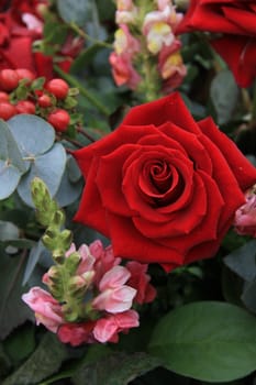 A single red rose in close up, some green and pink decorations in background