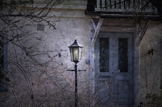 Vintage lamppost in front of a dilapidated old house with a blue door.