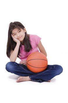 Ten year old Asian girl sitting on floor holding basketball, isolated on white