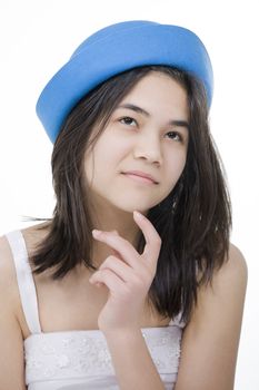 Beautiful young teen girl in blue hat, looking up with thoughtful expression, finger touching chin.Isolated on white