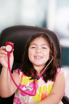 Cute little girl is playing doctor with stethoscope, isolated over white