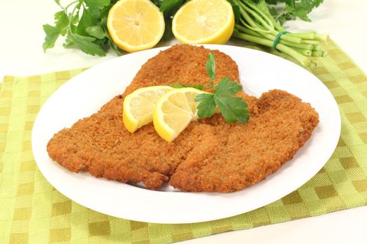 freshly fried Wiener Schnitzel with lemon slices and parsley on a napkin