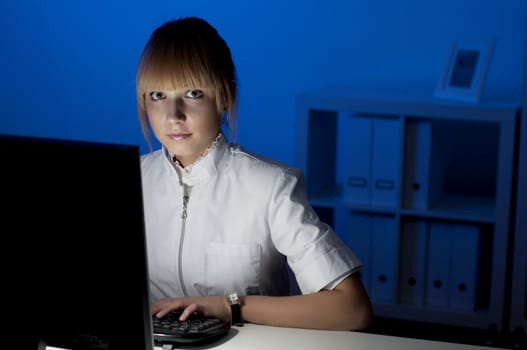 beautiful young woman doctor working at night in the office, smiling