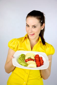 beautiful girl showing happy a plate full of fresh fruit with apple kiwi and strawberries
