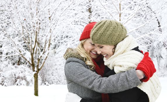 Portrait of two young girl friends hugging outdoors in winter