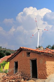 Old mud house in rural india with wind mill in the backdrop