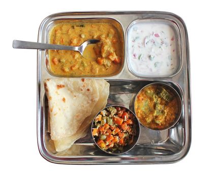 Traditional Indian bread chapati with curries, raitha and salad isolated on white