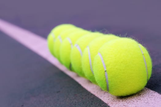 Tennis balls close up arranged in row on hard court synthetic tennis turf