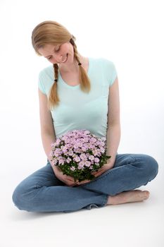 Smiling blonde sitting and holding pink flowers bouquet on white background