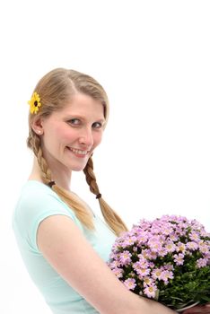 Pretty woman holding a posy of pink daisies looking sideways at the camera and smiling happily