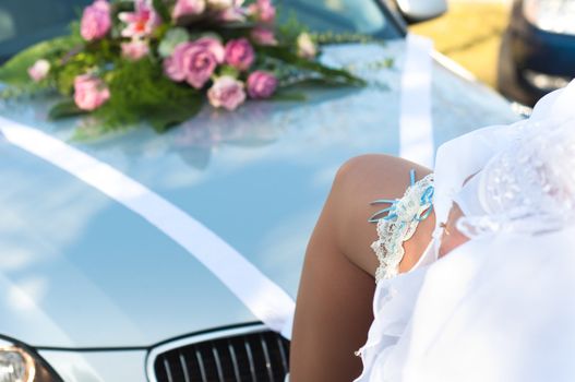 Leg of the bride with wedding garter on car