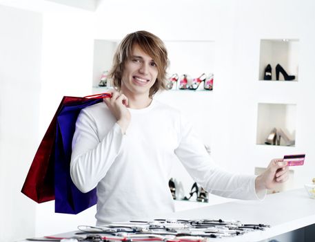 Young man at shopping mall checkout counter paying through credit card