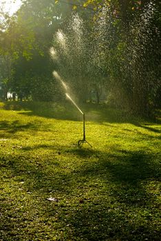 Lawn sprinkler spraying water over green grass