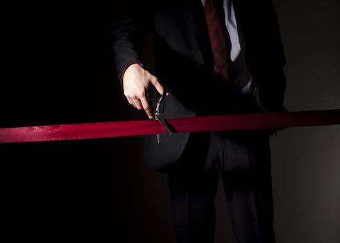 man in a suit, cuts a red tape, opening of event