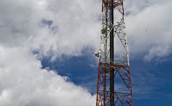 View of a radio tower against the sky with pluffy clouds
