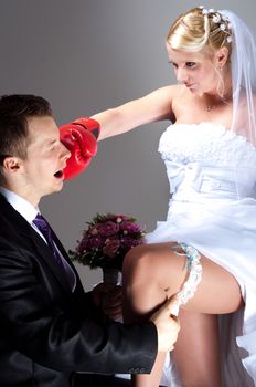 Young bride hitting groom while he takes off wedding garter