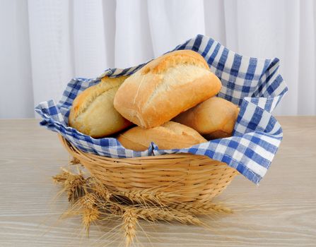 Fresh bread in a basket with a cloth cover ears of wheat