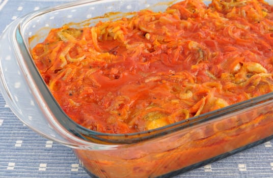 Marine fish baked with onions and carrots in tomato sauce