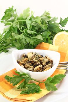 marinated mussels with flat leaf parsley in a bowl on checked napkin