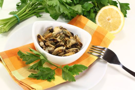 marinated mussels with flat leaf parsley in a bowl on an orange napkin