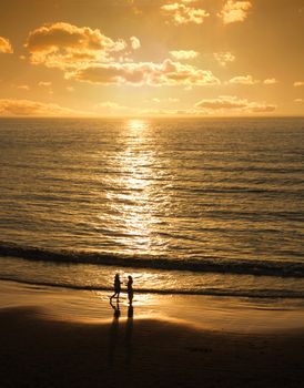 Male and female silhouettes meet at romantic sunset beach