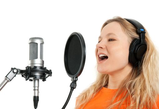 Female singer in headphones singing with studio microphone. Isolated on white background.
