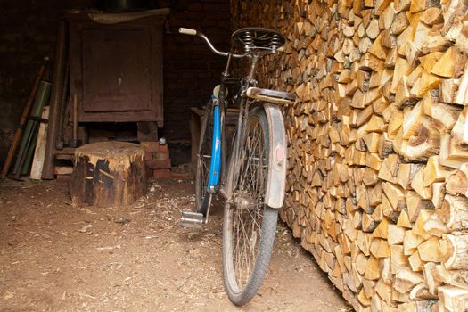 rusty old bicycle in a shed with firewood