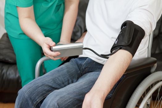 Blood pressure check for young adult in wheelchair.