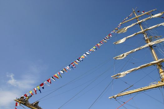 Sailing vessel with white sails on a mast and alarm flags