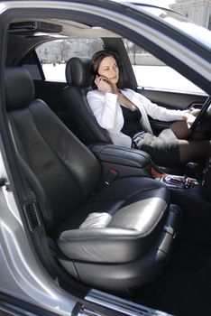 Smiling happy European businesswoman talking on cell phone in the car
