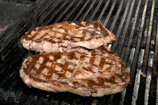 two large watering steak cooked on the grill
