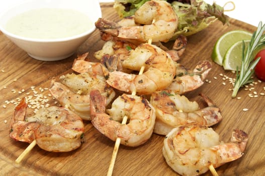 Grilled Shrimp on a wooden plate with the sauce and greens