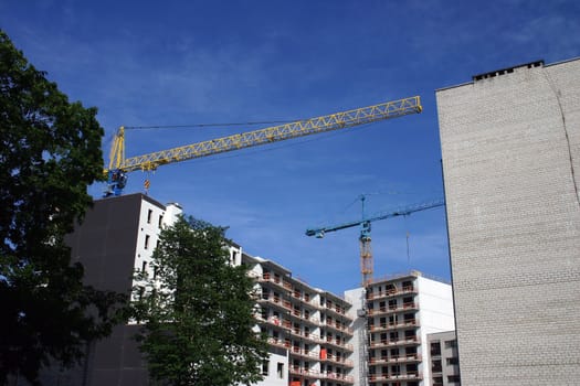 Building of the house by two tower cranes, blue and yellow