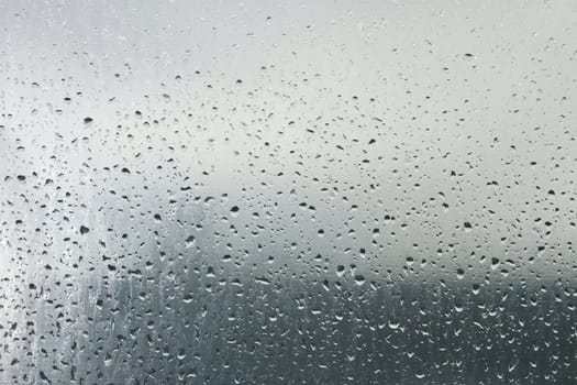 Water droplets on a transparent surface. On the background the blurry objects