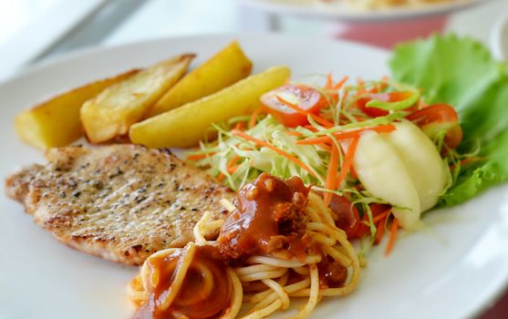 Grilled pork steak served with chips, potatoes and vegetables , macaroni