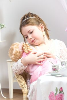 A beautiful little girl having a tea party with her baby doll