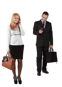 Studio shot of a young couple using mobile phones against a white background.