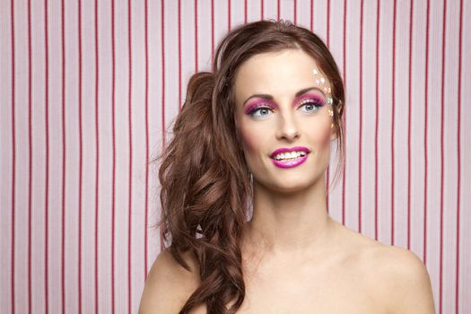 Young woman with colorful makeup and star candy glued to her face
