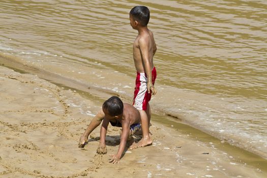 Unknown Kids playing with sand and water by the river in Belaga Sarawak, Malaysia
