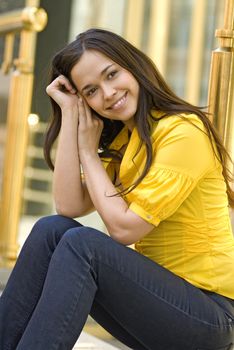 beautiful young woman in yellow blouse sits on the street