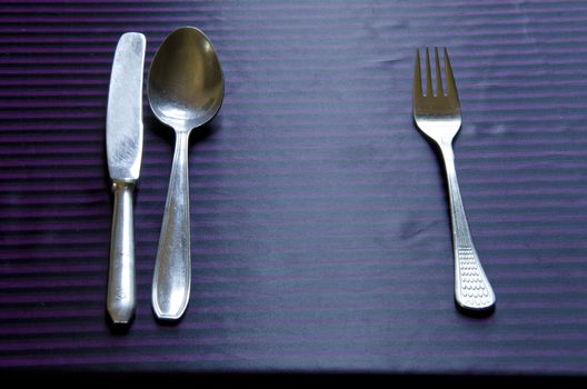 Vintage metal flatware tableware placed on the cloth by etiquette. Spoon, fork and knife.