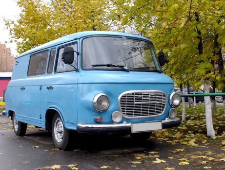 Blue vintage minivan on the road, autumn shot
