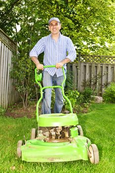 Man with lawn mower in landscaped backyard