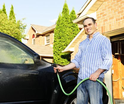 Man washing his car on the driveway